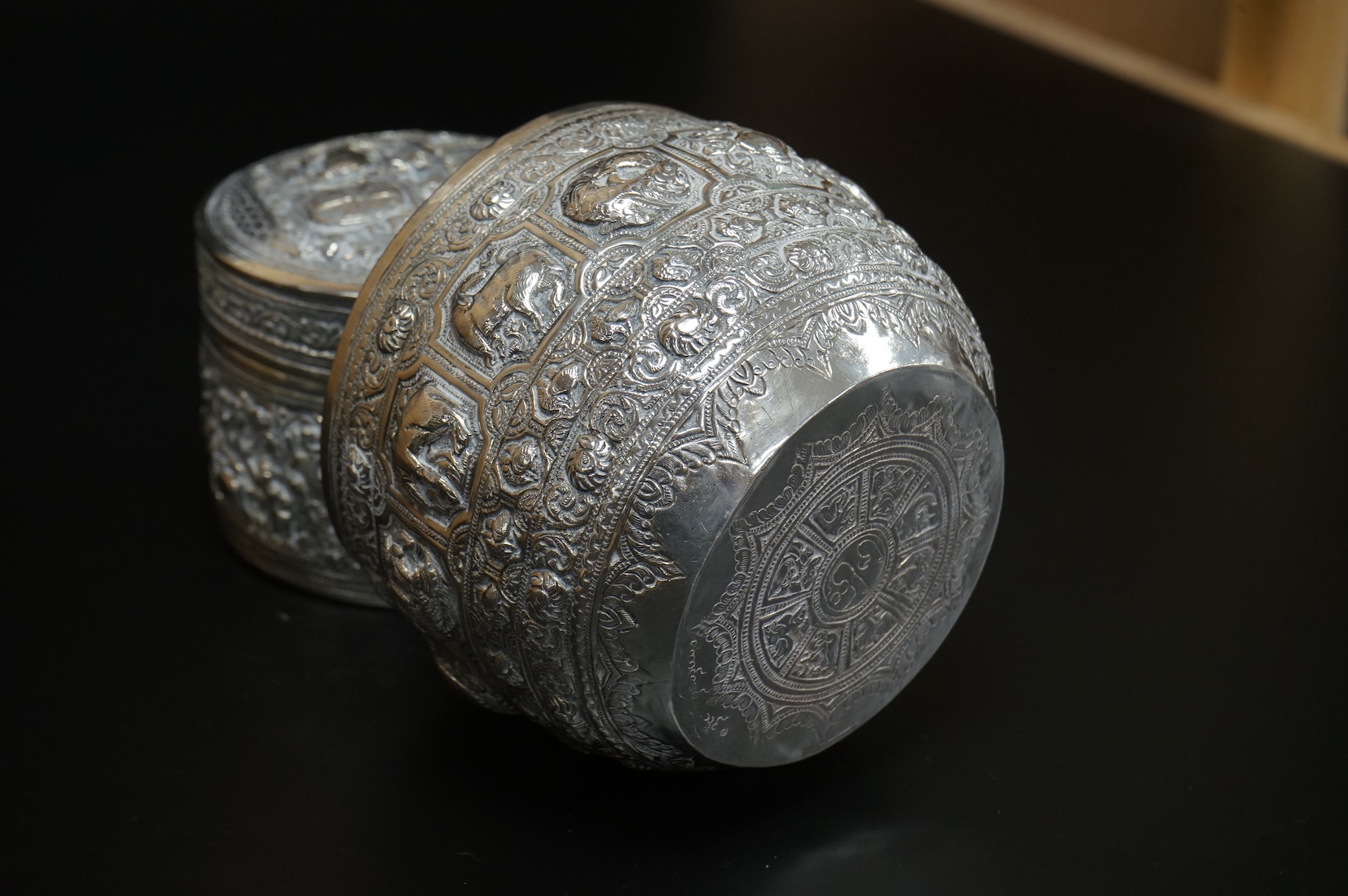 A Burmese embossed white metal circular bowl, signature to the base, diameter 11.4cm, together with a similar circular box and cover, 17oz.